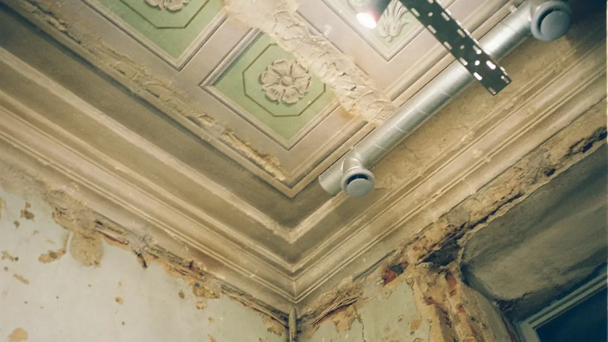 A damaged ceiling corner with water stains and peeling plaster - Basement Leak Detection in Cape Girardeau