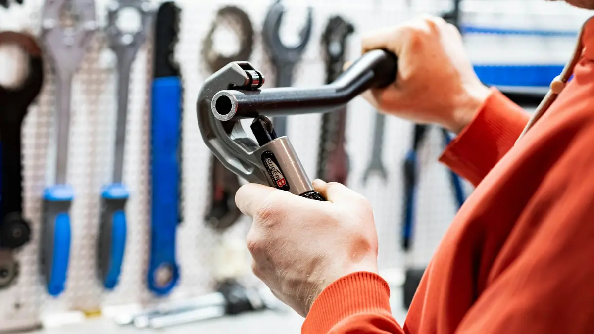 A person gripping a pipe cutter in front of a pegboard of wrenches - Basement Leak Detection in Cape Girardeau