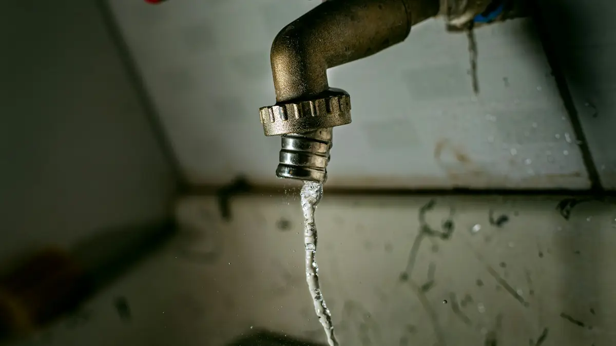 A brass tap with a thin stream of water running down a wall - Basement Leak Detection in Cape Girardeau